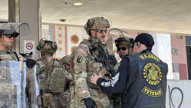 U.S. Army veteran walks up to the National Guard on duty in front of the U.S. Citizenship and Immigration Services Building in Los Angeles during June 2025 ICE protests.